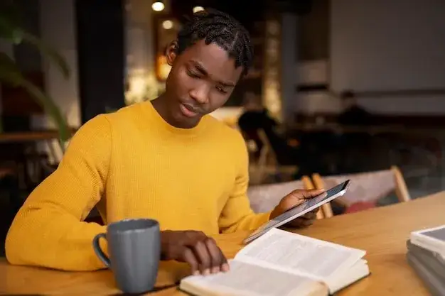 Osoba czytająca papierową książkę w kawiarni