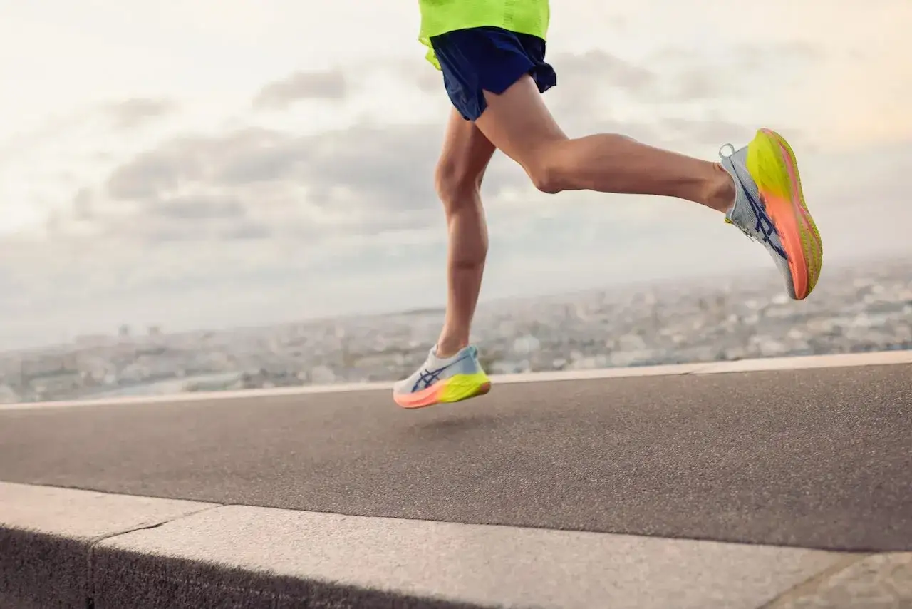 Biegacz w kolorowych butach na tle miasta. Zastanawiasz się, ile km biegać na początek? Zacznij od małych dystansów.