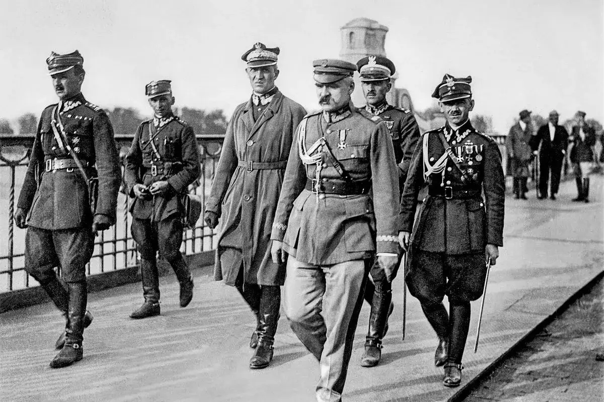 Marszałek Piłsudski i inni oficerowie w mundurach maszerują. Scena z okresu dwudziestolecia międzywojennego.