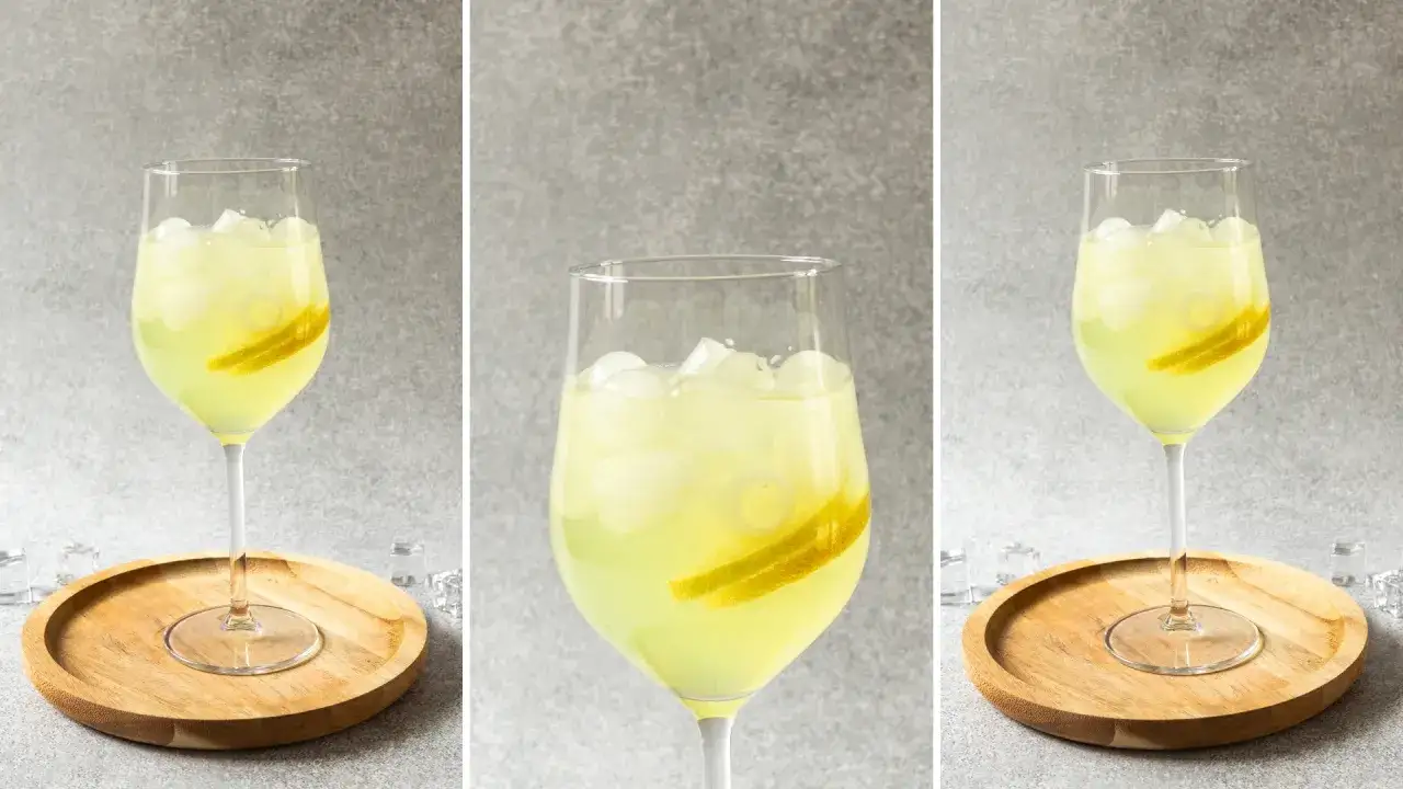 Orzeźwiający limoncello spritz przepis: jasny, cytrynowy drink z lodem i plasterkami cytryny w kieliszku na drewnianej podstawce.