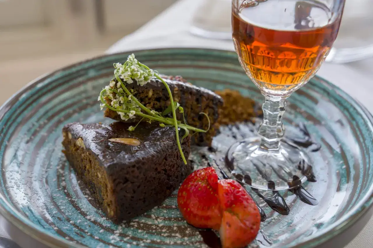 Słodkie ciasto z bakaliami i owocami, idealne jako inspiracja, co przywieźć z Maderę do jedzenia. Do tego kieliszek bursztynowego likieru.