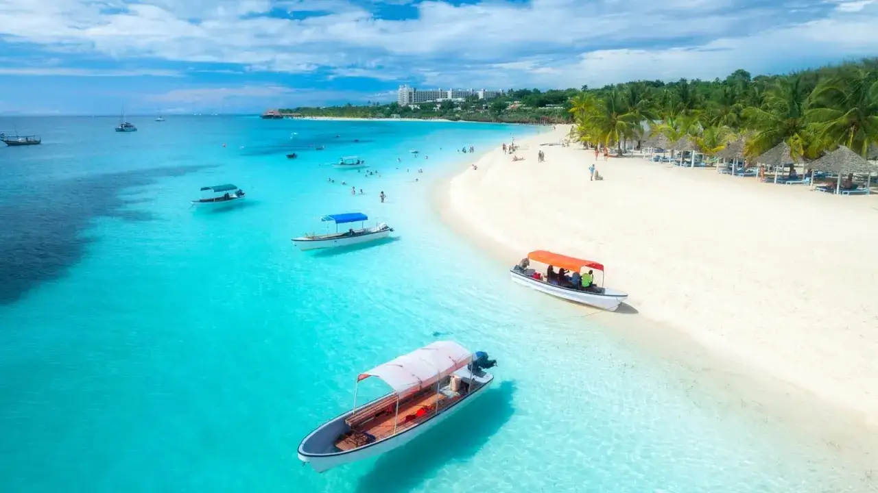 Idealne miejsce, gdzie na wakacje w sierpniu: turkusowa woda, biała plaża, palmy i łodzie. Rajskie widoki.
