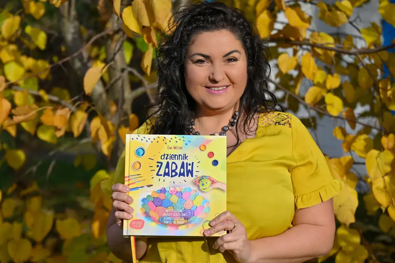 Kobieta w ż&oacute;łtej bluzce trzyma książkę 
