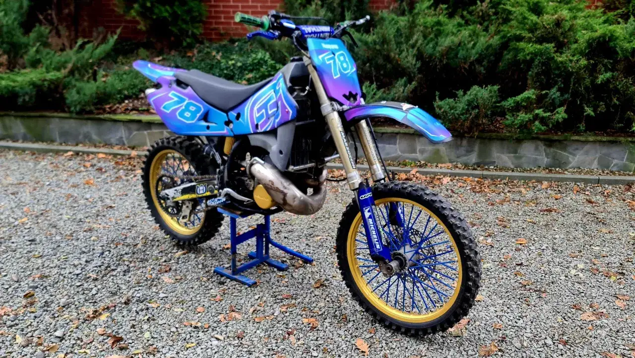 Wyjątkowy Husqvarna CR 250 z kolorowym malowaniem i złotymi felgami, gotowy na wyzwania toru.
