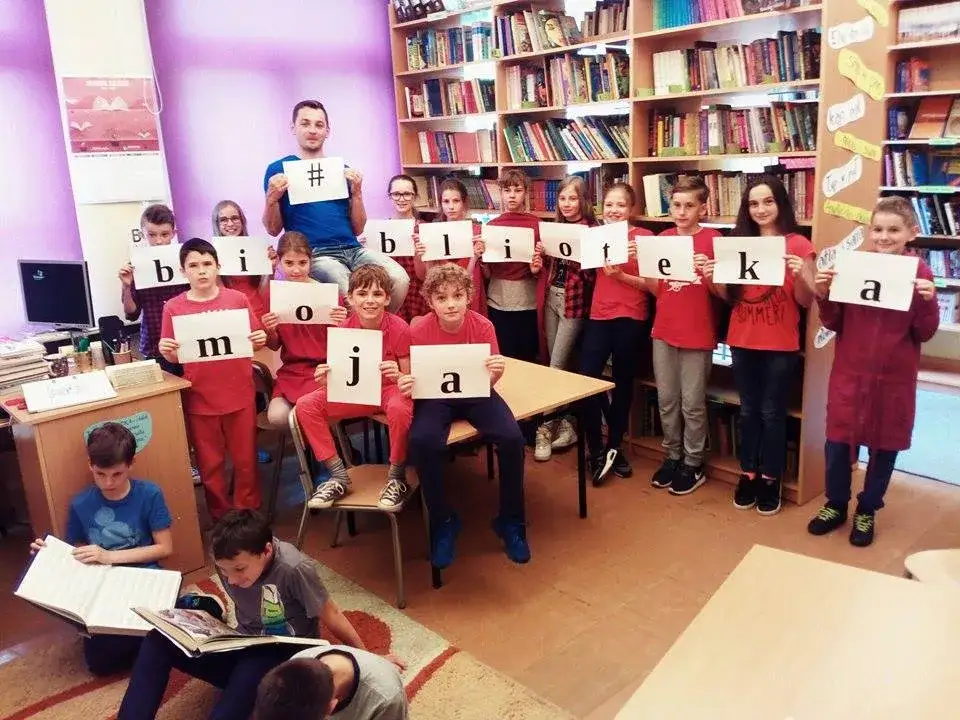 Grupa uczniów dyskutująca o książkach, nowoczesna biblioteka szkolna