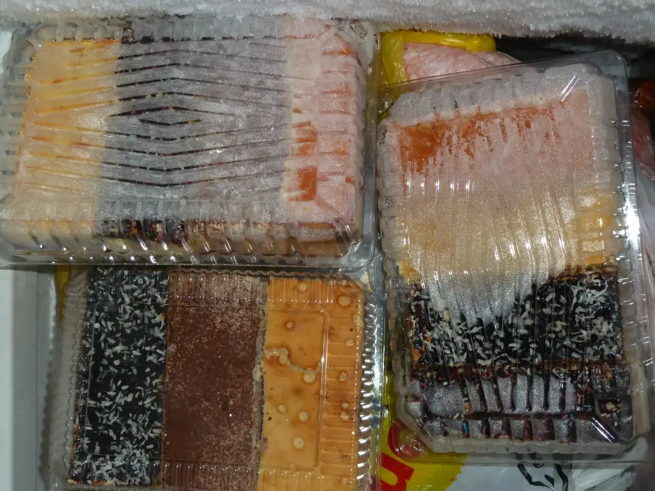 W zamrażarce widać kilka pojemników z ciastkami. To dowód, że można mrozić ciasta, by dłużej cieszyć się ich smakiem.