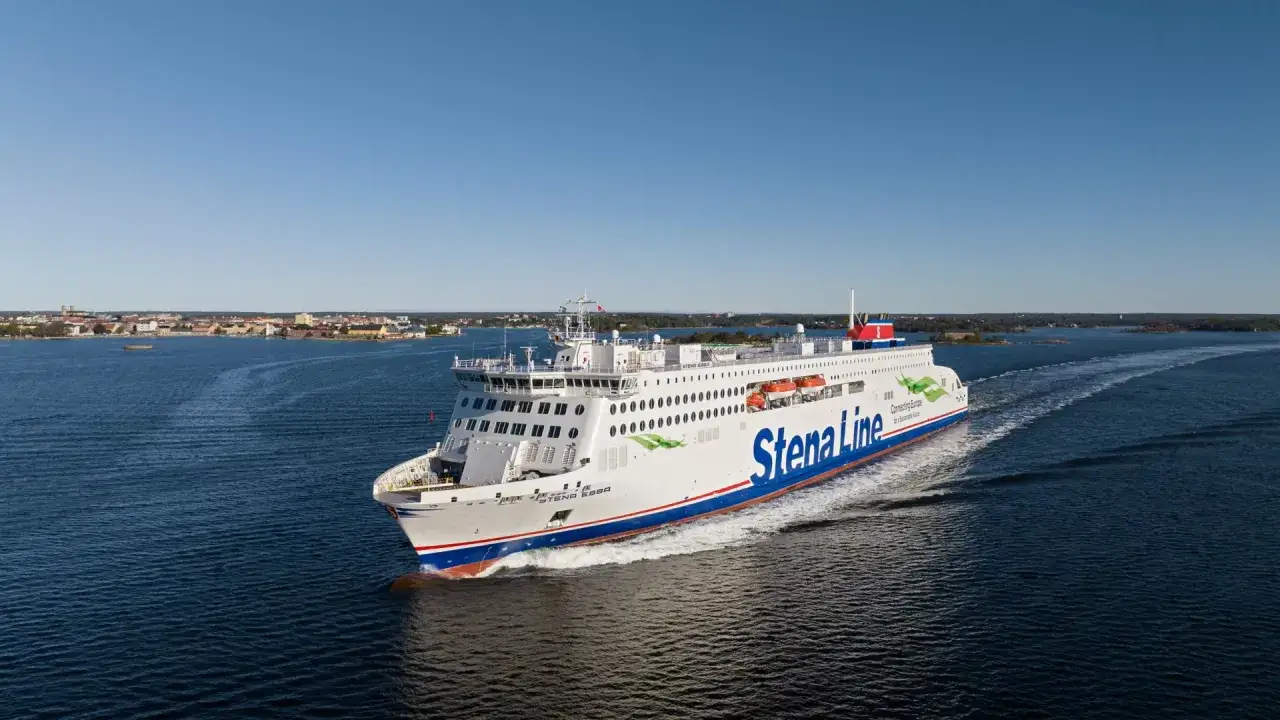 Prom na wodzie z napisem Stena Line. Statek płynie w kierunku miasta na horyzoncie, oferując podróżnym widoki i atrakcje.