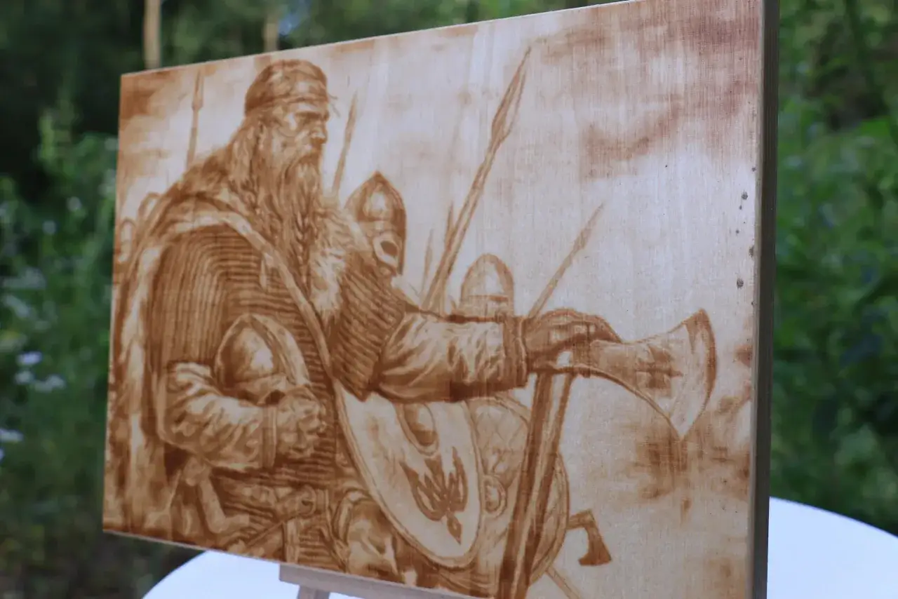 Wypalanie w drewnie przedstawia wiking&oacute;w w zbrojach, z toporami i tarczami, gotowych do walki.