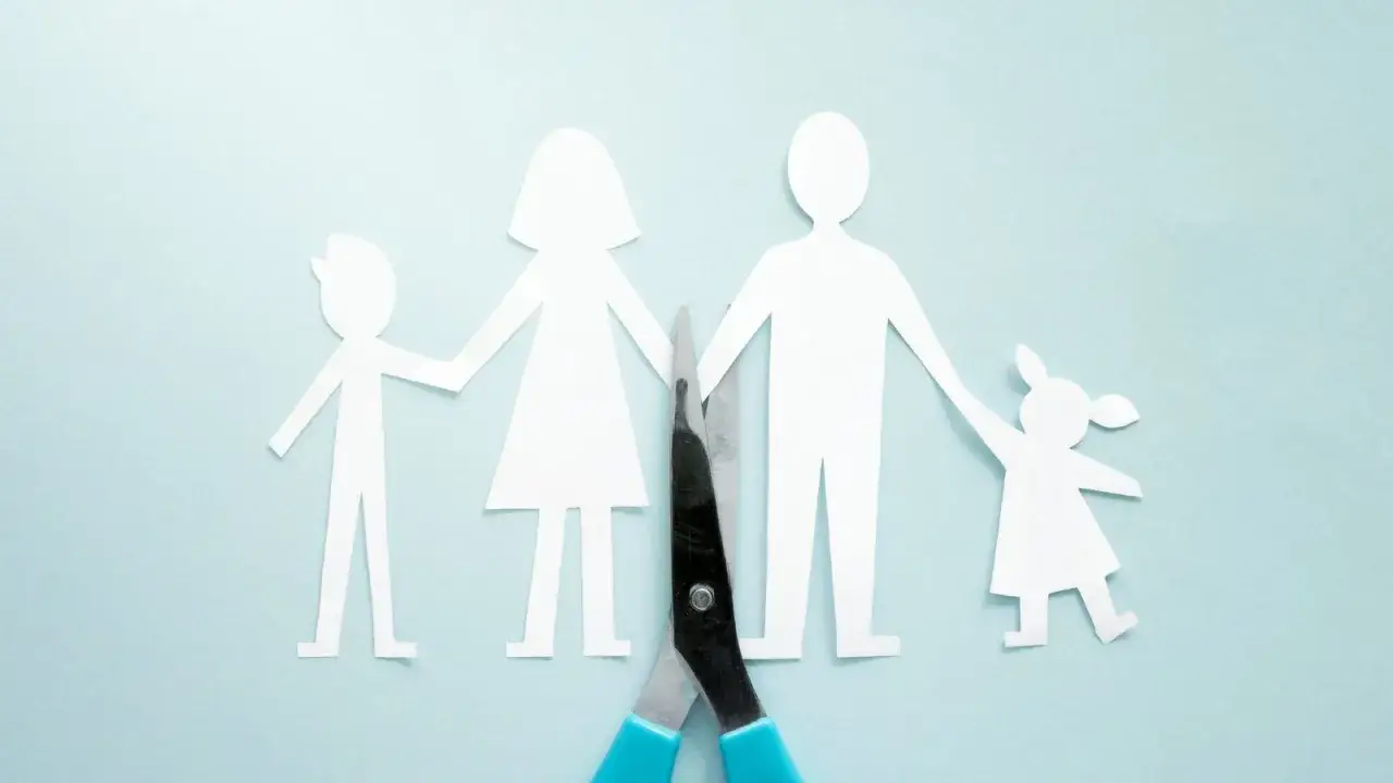 Rozwód a dzieci: para papierowych ludzików, rodzice rozdzieleni nożyczkami, dzieci trzymające się za ręce.