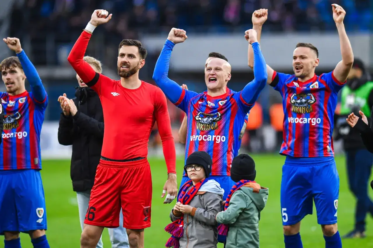 Piast Gliwice zawodnicy świętują z kibicami. Piłkarze w czerwonych i niebiesko-czerwonych strojach unoszą ręce w geście radości.