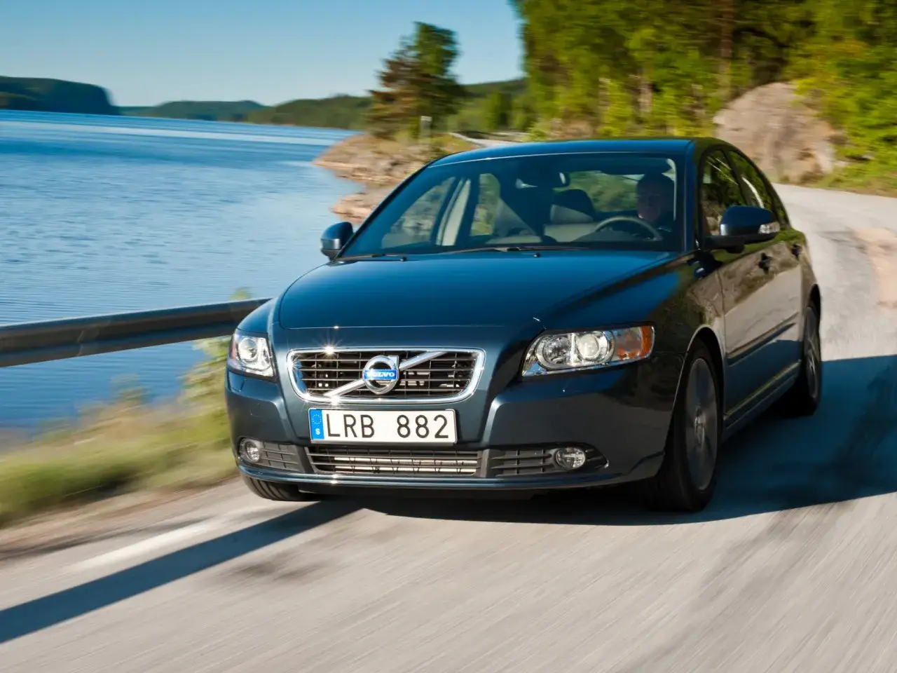 Ciemny Volvo S40 jedzie malowniczą drogą nad jeziorem. Poznaj jego wymiary i możliwości.