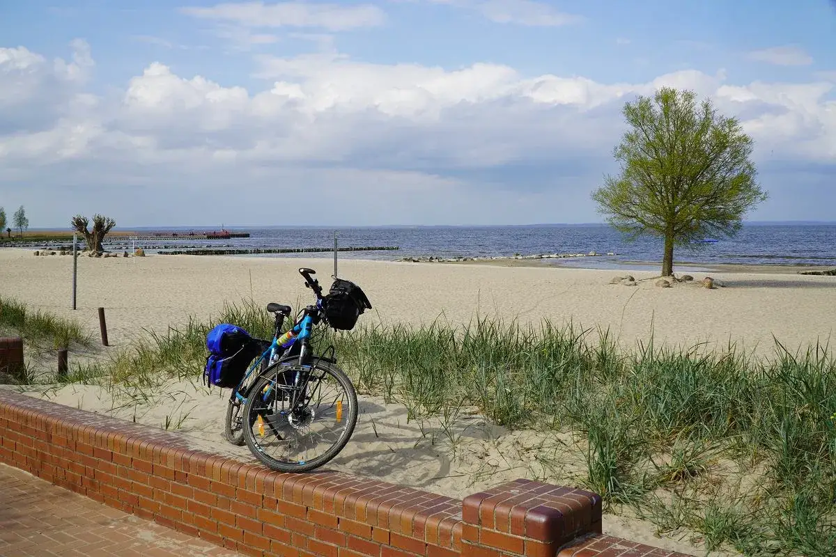 Rower z sakwami na plaży, gotowy do podróży. Zastanawiasz się, ile jest ze Szczecina do morza? Ta malownicza trasa rowerowa zaprowadzi Cię prosto nad wodę.