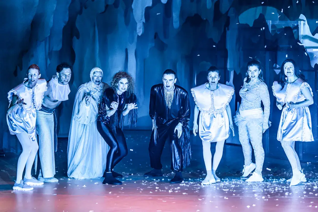 Aktorzy w fantazyjnych strojach na scenie, tworzący jedne z najlepszych spektakli teatralnych.