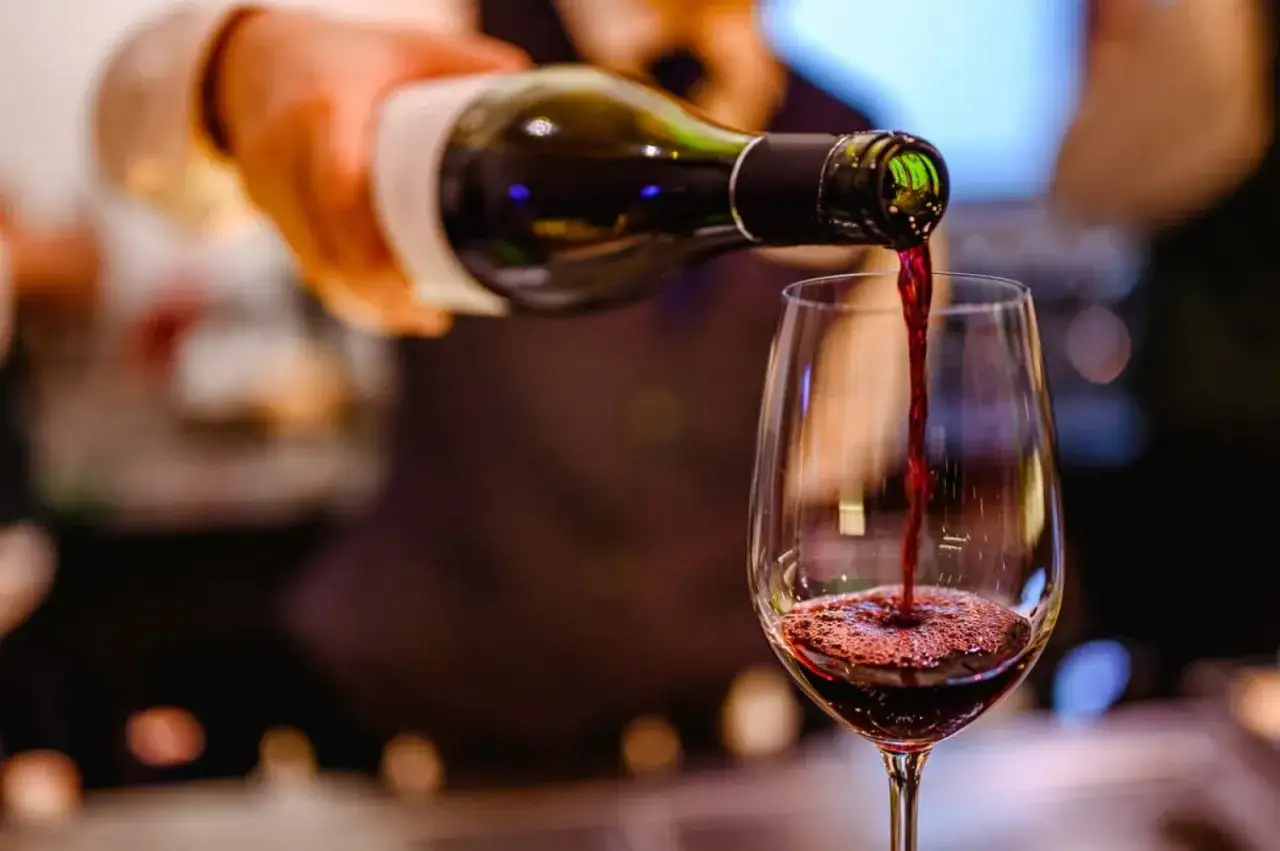 Czerwone wino nalewane do kieliszka. Idealne pytanie: jakie wino do obiadu?