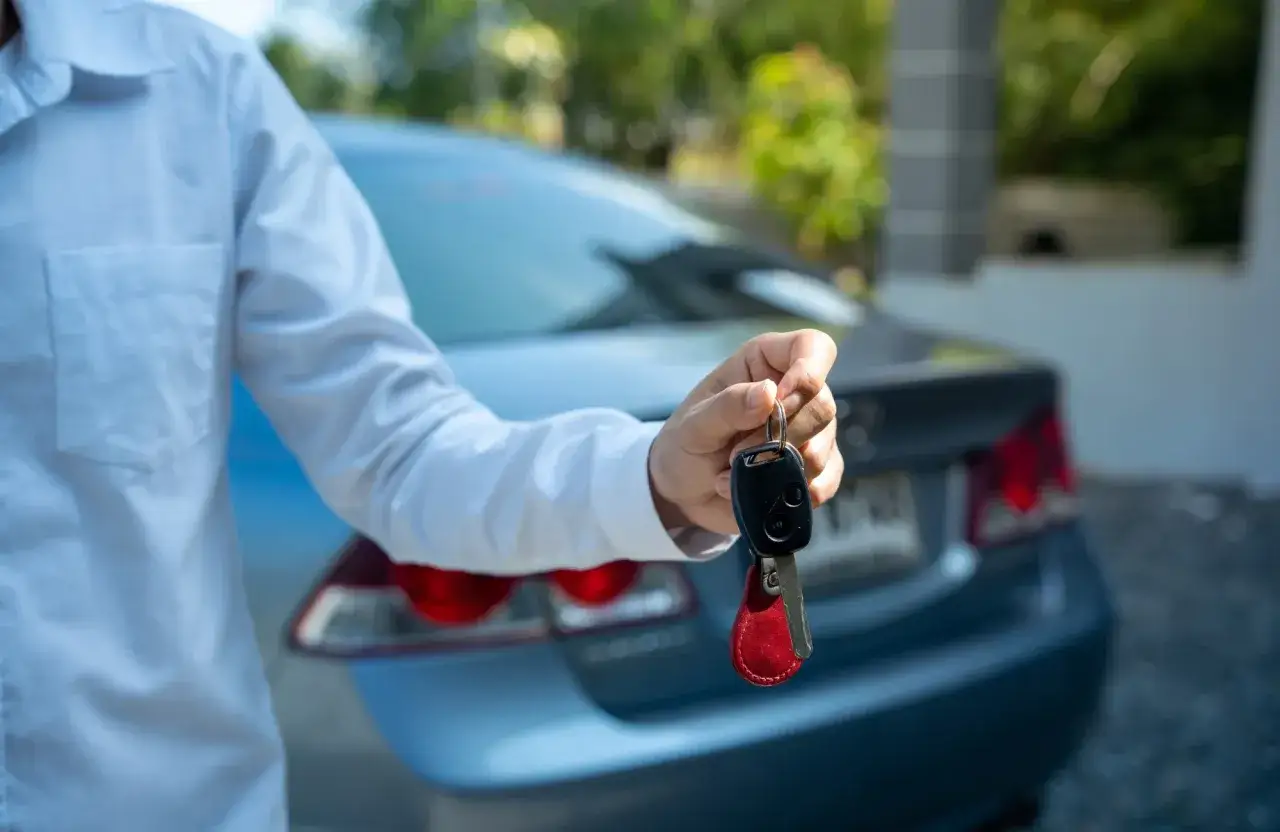 Mężczyzna w białej koszuli trzyma kluczyki do samochodu. Chcesz odstąpić leasing? Ten samochód może być Twój!