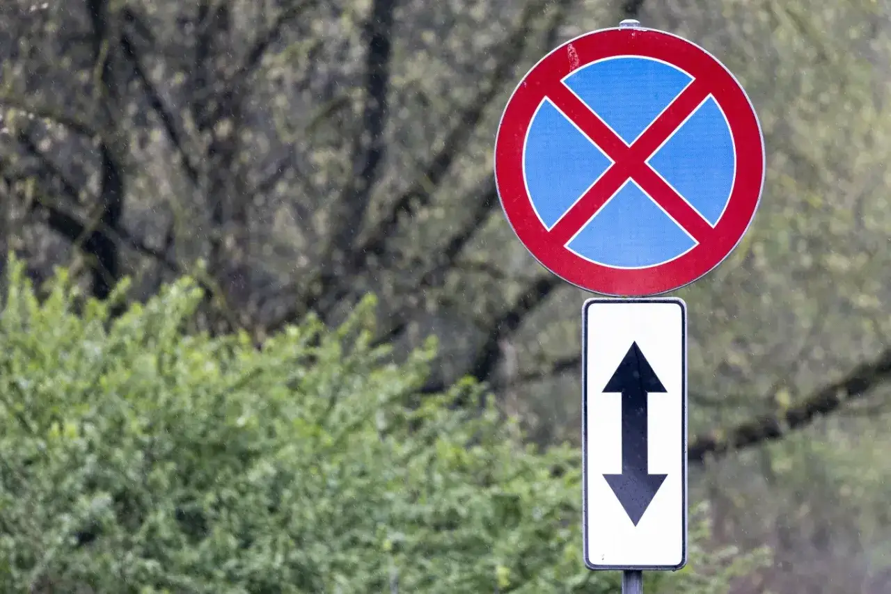 Znak zakaz postoju z symbolem dwóch strzałek w pionie.