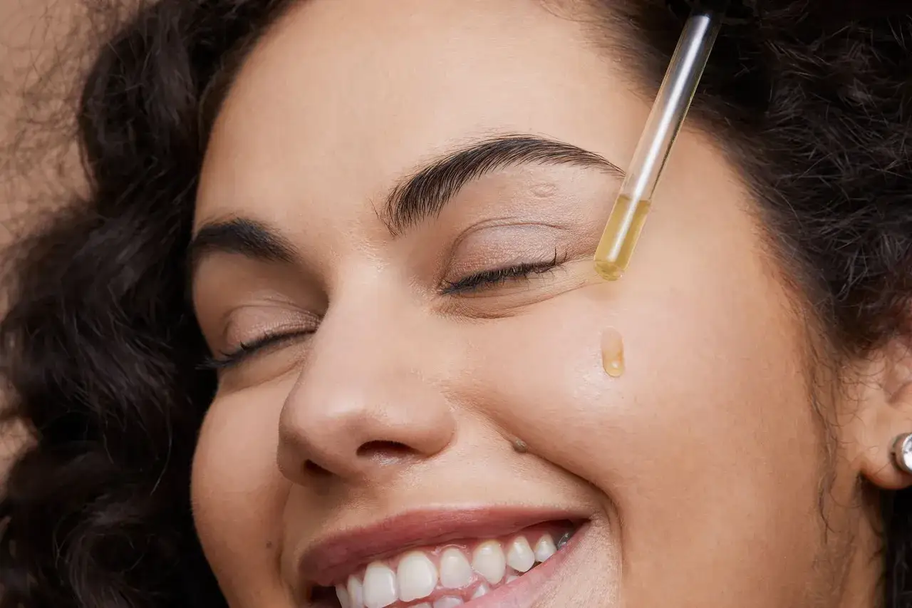 Kropla oleju arganowego na policzku, pokazująca, jak stosować olej arganowy na twarz dla nawilżenia i blasku.