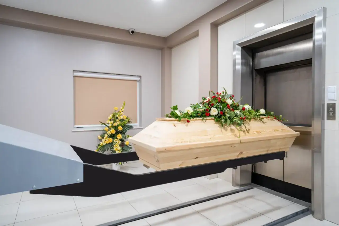 Drewniana trumna z kwiatami na podnośniku. Czy kremacja boli zmarłego? To pytanie nurtuje wielu, ale proces ten jest bezbolesny.