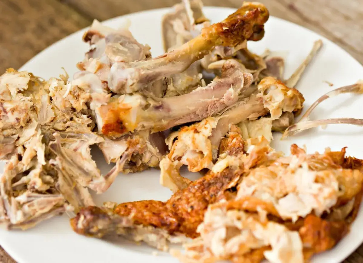 Resztki pieczonego kurczaka na talerzu, idealne na bulion z pieczonych kości drobiowych głęboki umami bez dodatku wołowiny.