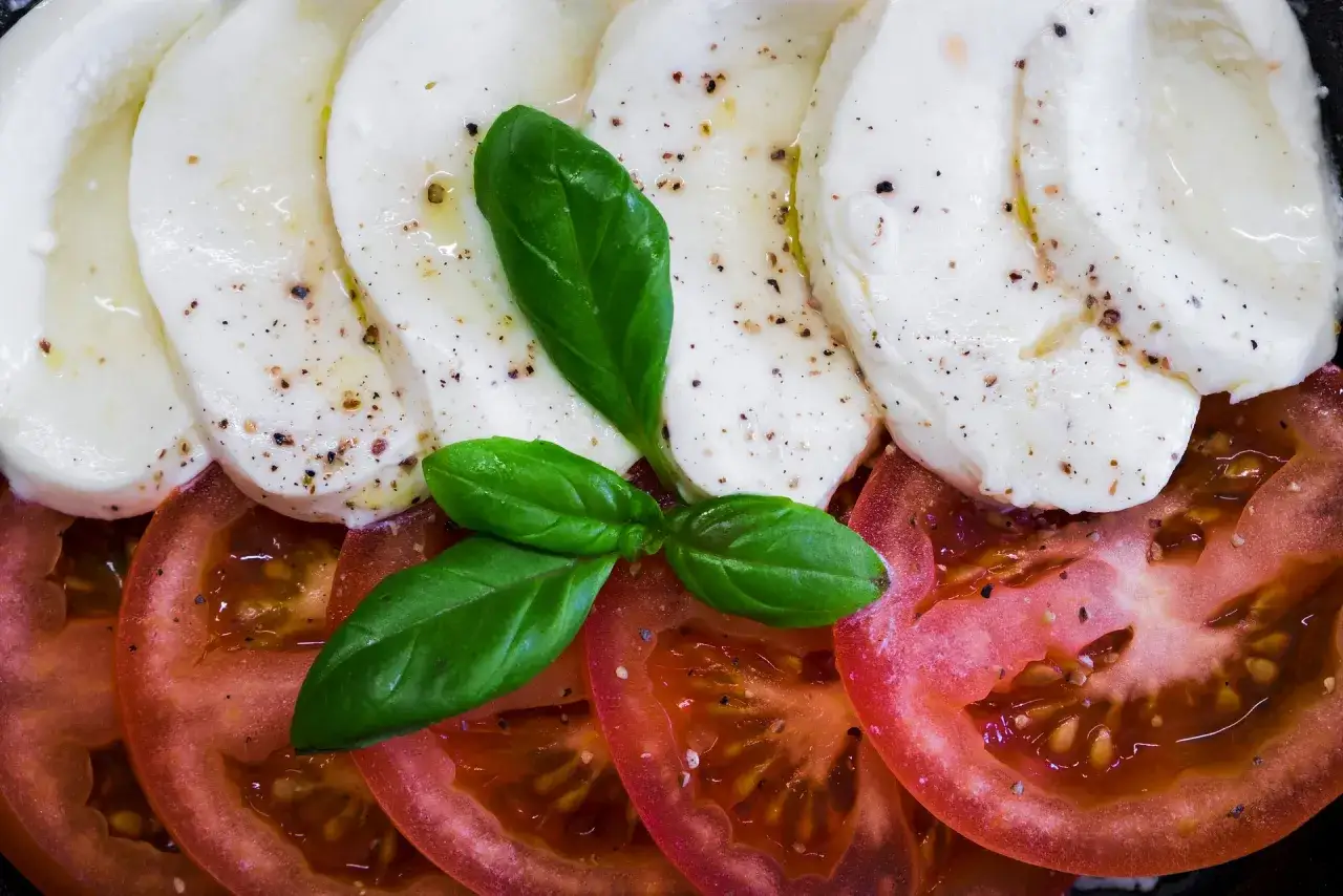 Sałatka caprese z plastrami pomidora, mozzarelli i listkami bazylii. Czy mozzarella podnosi cukier? Ten przysmak jest niskowęglowodanowy.