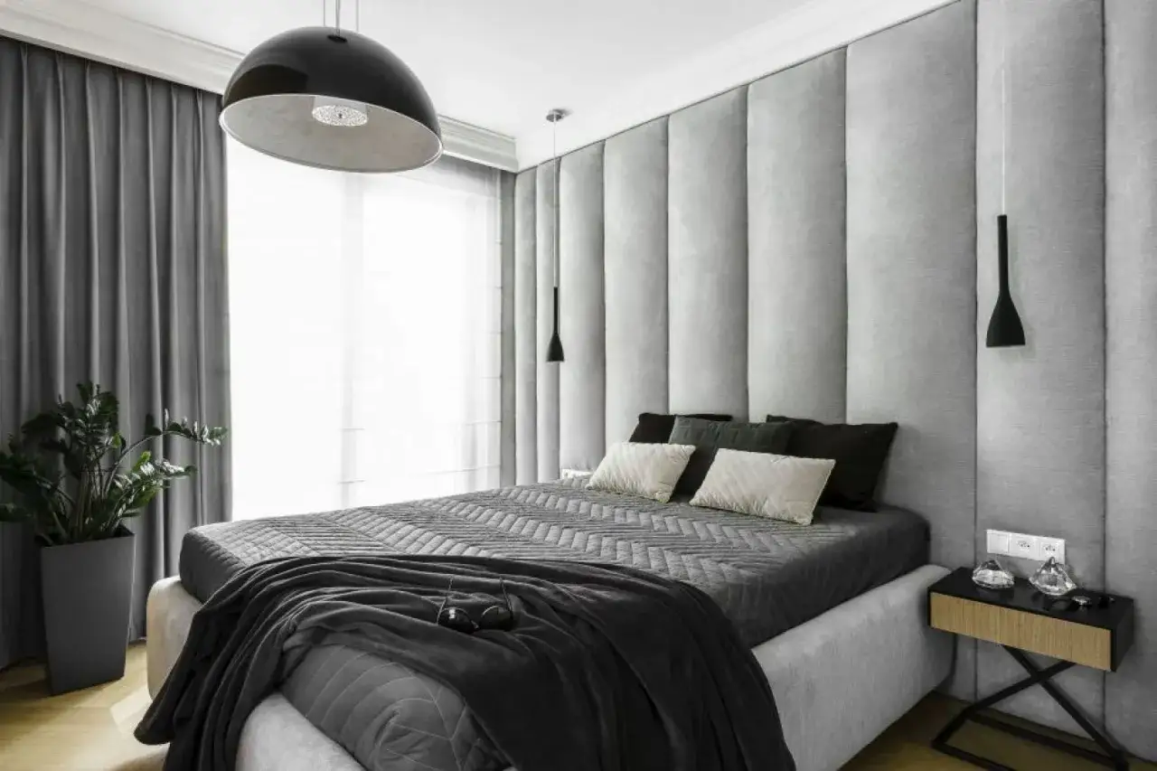 Nowoczesna sypialnia z szarymi panelami tapicerowanymi za ł&oacute;żkiem. Czy panele tapicerowane można przykleić na tapetę? Tak, to możliwe!