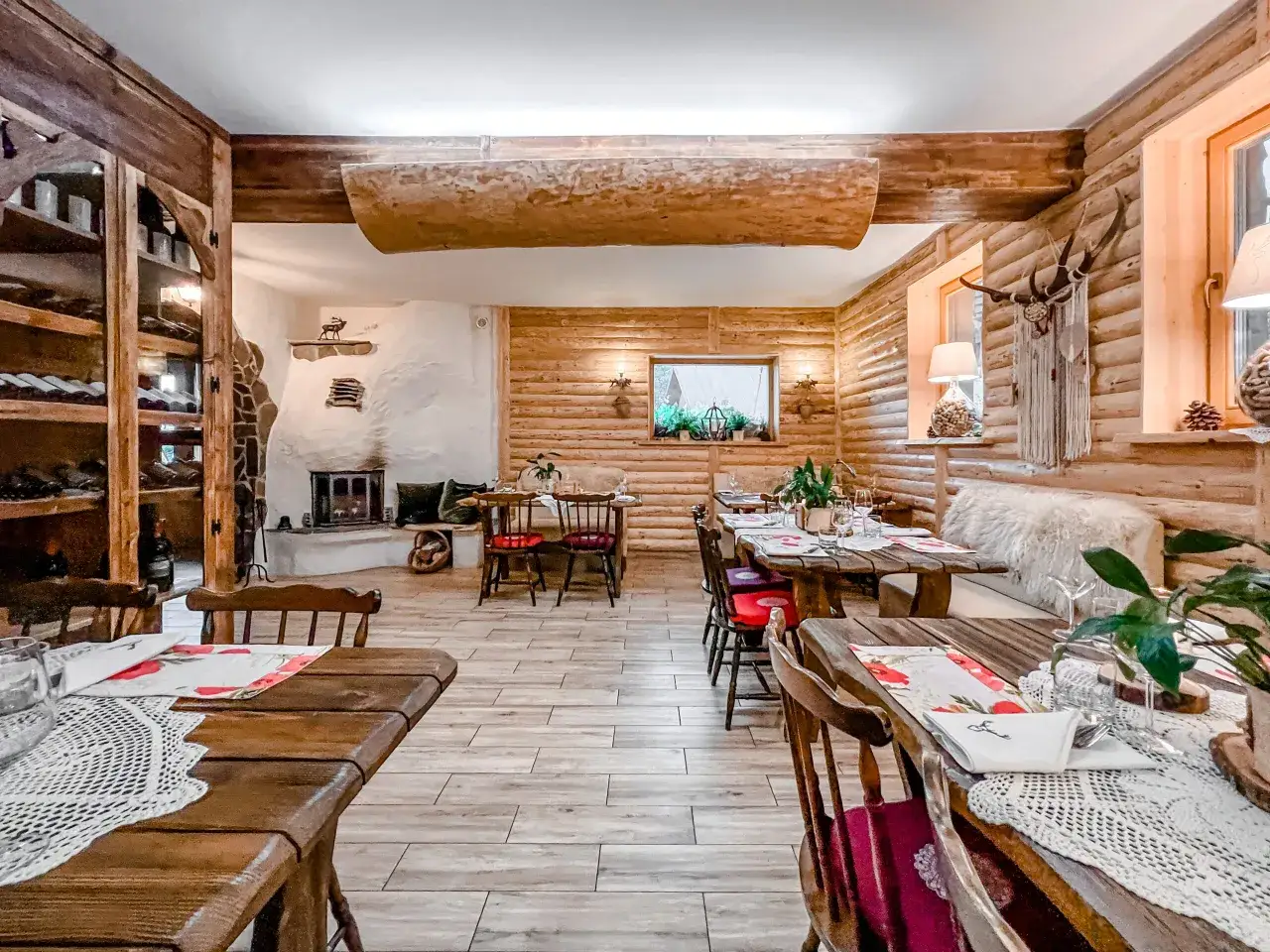 Przytulna bac&oacute;wka z drewnianymi meblami, kominkiem i winnicą. Wnętrze nawiązuje do g&oacute;rskiego klimatu, a dekoracje z porożem i motywami zwierzęcymi podkreślają charakter miejsca.