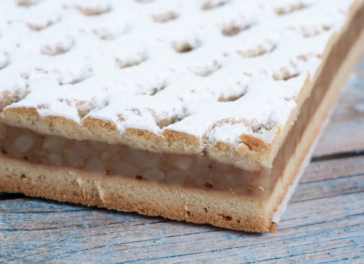 Pyszna szarlotka z kratką z ciasta, posypana cukrem pudrem. Zastanawiasz się, ile czasu piec szarlotkę? Ta wygląda idealnie!