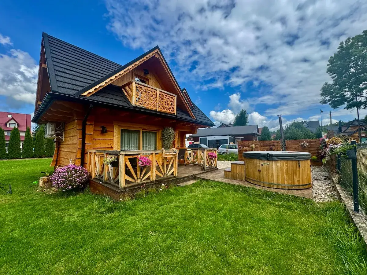 Drewniany domek w Bukowinie Tatrzańskiej z bali, z werandą, balkonem i drewnianą balią do kąpieli na świeżym powietrzu.