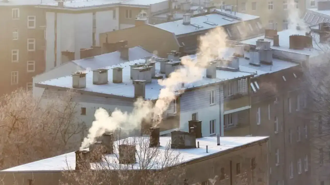 Dym z komin&oacute;w na tle zaśnieżonych dach&oacute;w świadczy o zanieczyszczeniu i złej jakości powietrza w mieście.