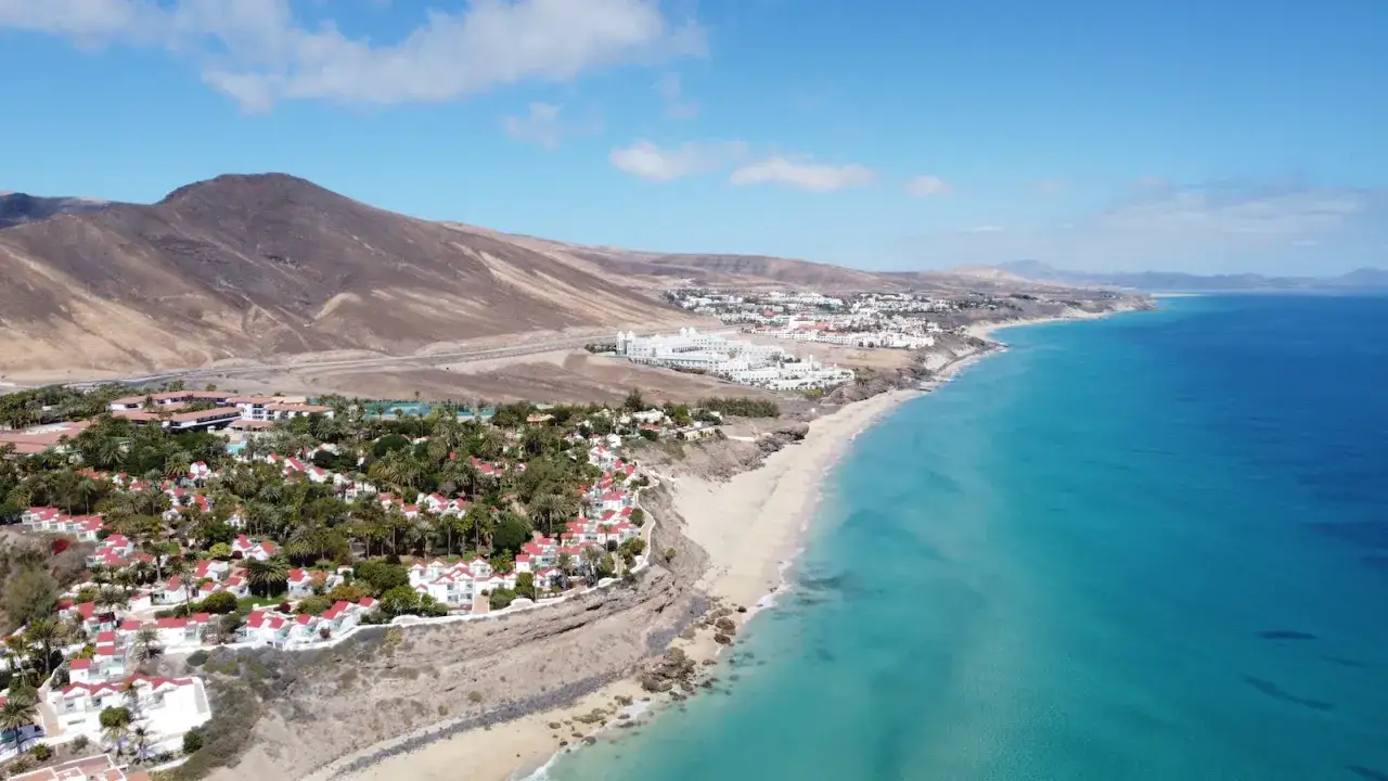 Wybrzeże Fuerteventury z białymi hotelami i palmami, w oddali g&oacute;ry. Czy to Teneryfa czy Fuerteventura?