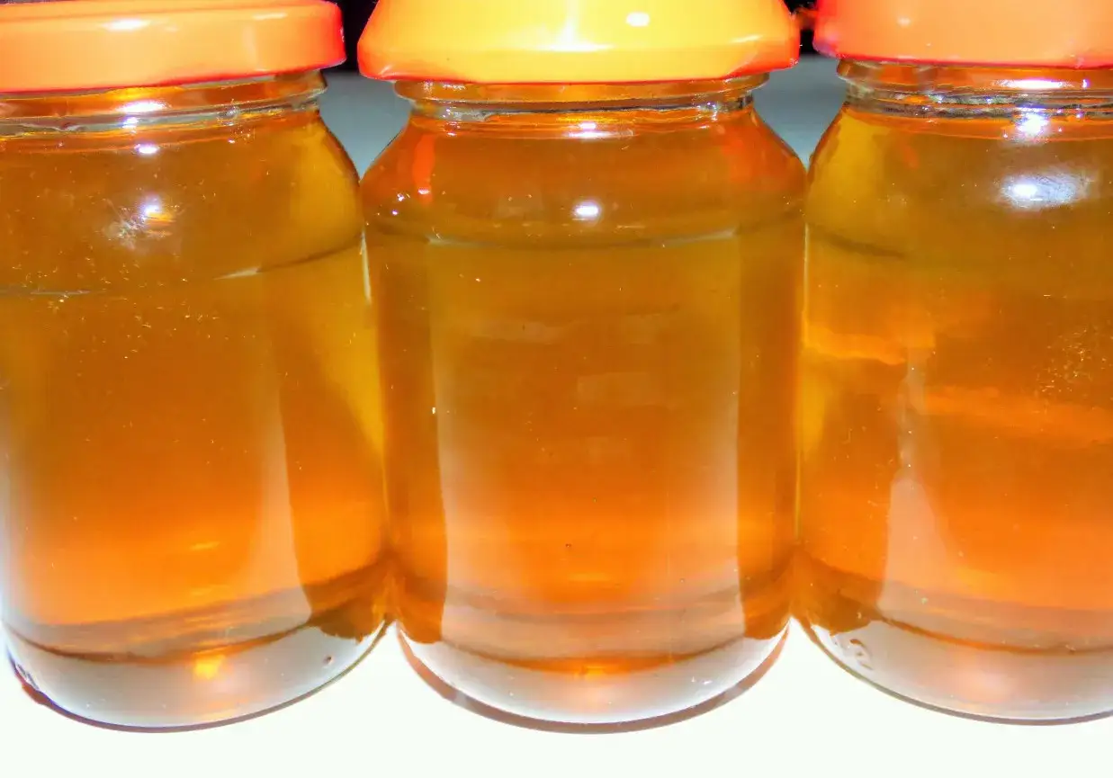 Trzy słoiki z bursztynowym syropem z mniszka, gotowe na zimowe wieczory.