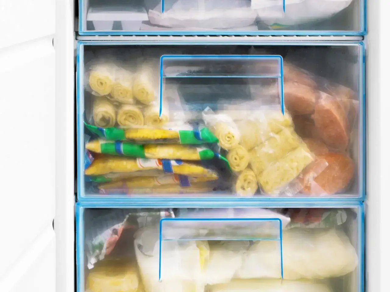 Zamrożone warzywa w szufladach zamrażarki. Widać mrożone fasolki, kukurydzę, a także inne produkty, które można mrozić.