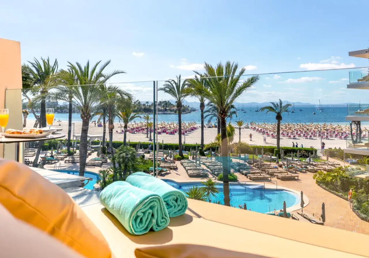 Widok z balkonu na plażę Majorki, basen i palmy. Idealne miejsce na relaks, zastanawiasz się, ile kosztuje tygodniowy pobyt na Majorce?