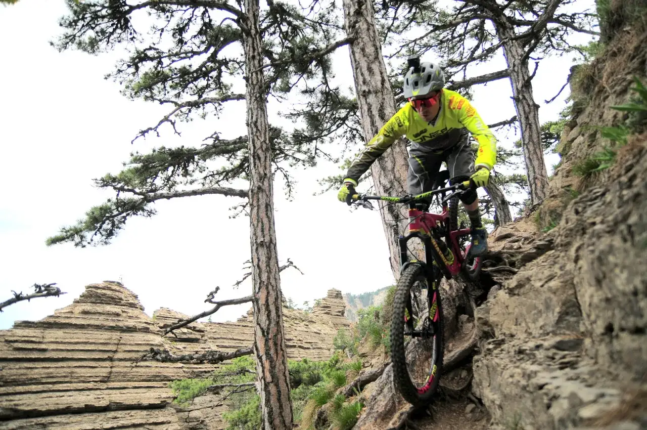 Rowerzysta w kasku z kamerą zjeżdża po kamienistym, stromym szlaku. To właśnie **enduro co to** za dyscyplina!
