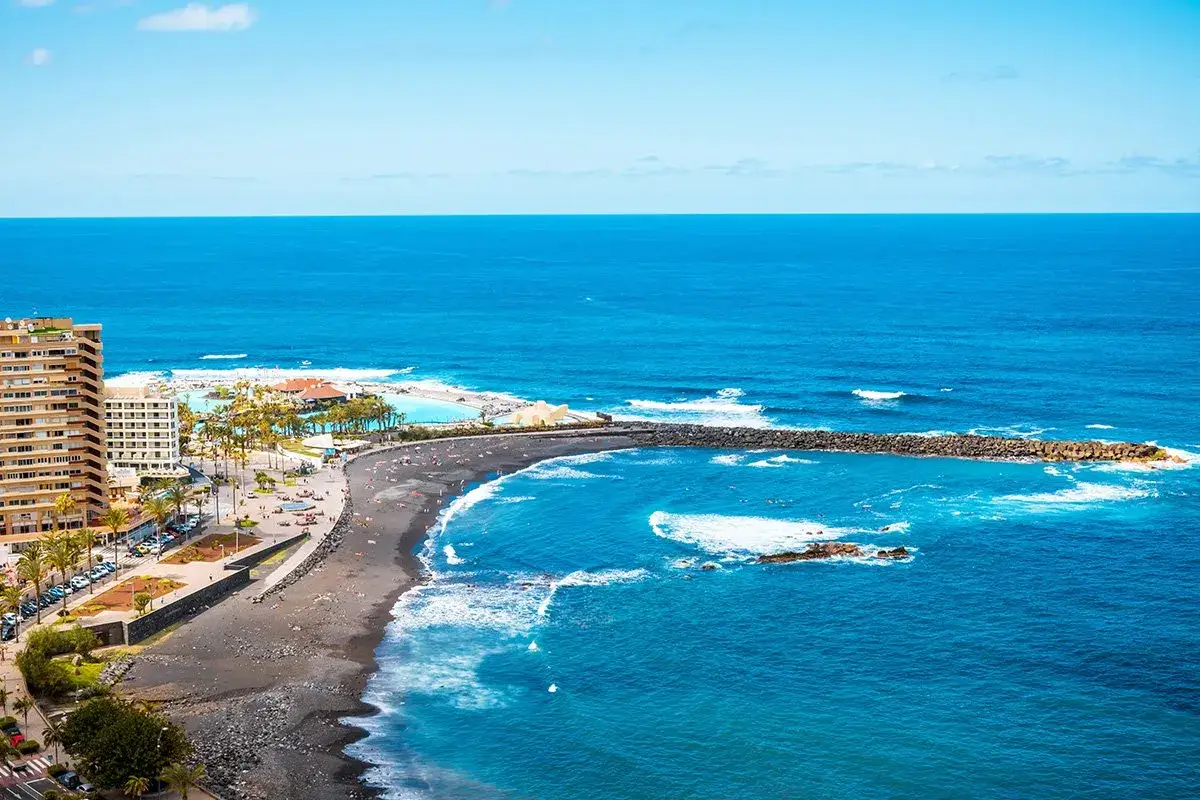 Puerto de la Cruz atrakcje: czarna plaża, baseny z wodą morską i hotel nad oceanem.