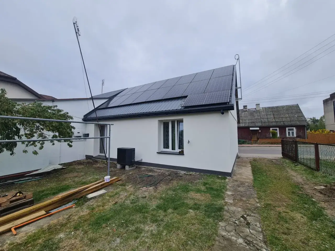 Dom z panelami fotowoltaicznymi na dachu. Czy montaż paneli fotowoltaicznych wymaga zgłoszenia? Instalacja wygląda na nową, gotową do pracy.