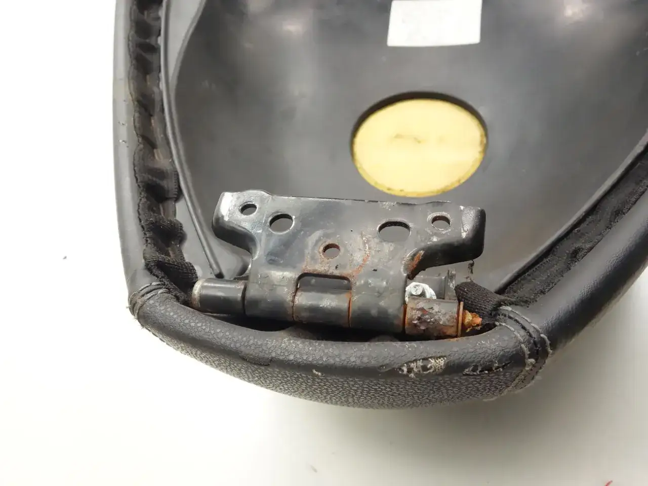 Zawias siedzenia skutera Peugeot. Pokazuje, jak otworzyć siedzenie w skuterze Peugeot, widoczny mechanizm zawiasowy.