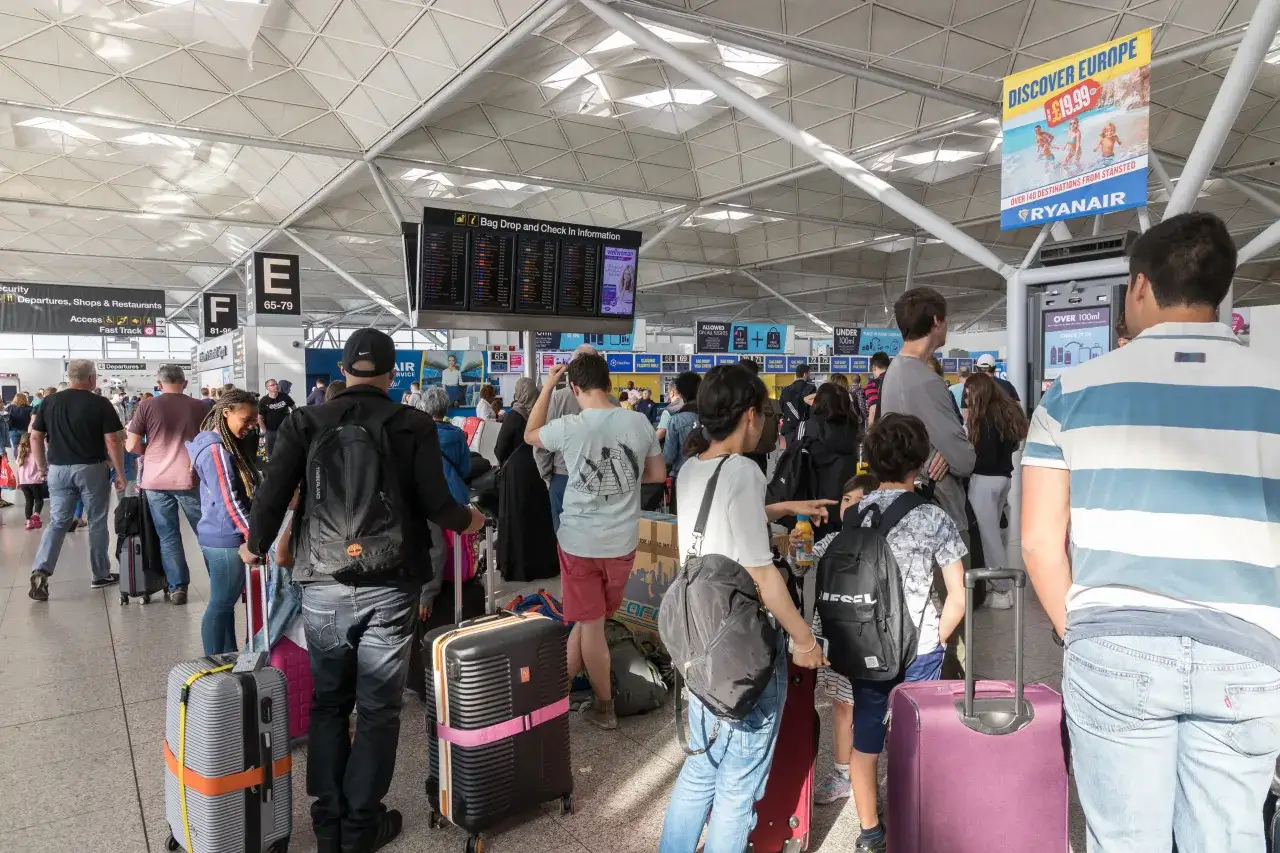 Tłum ludzi z bagażami na lotnisku, zastanawiający się, czy do Rzymu potrzebny jest paszport.