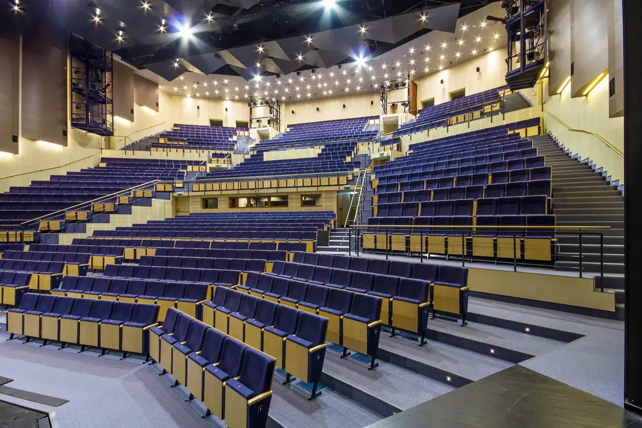 Widok na puste rzędy granatowych foteli w nowoczesnej sali Teatru Muzycznego w Gdyni. Trudno określić, ile miejsc ma teatr muzyczny w Gdyni, ale jest ich mnóstwo!