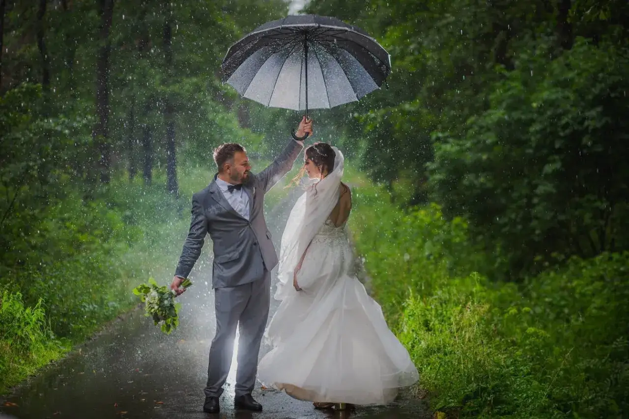 Para młoda pod parasolem w deszczu. Skutki braku planu awaryjnego na wesele w plenerze co jeśli spadnie deszcz.