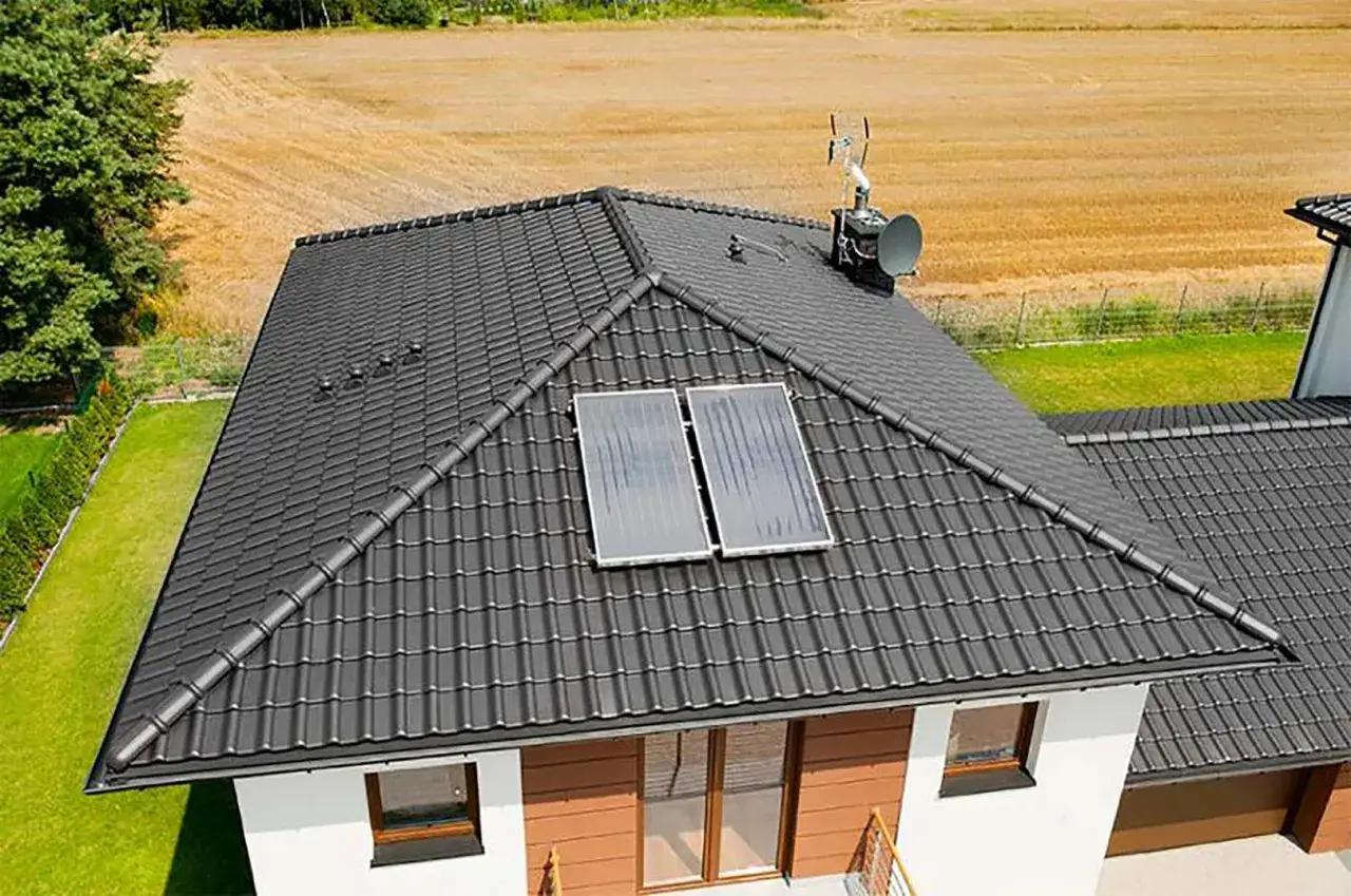 Nowy dach dwuspadowy z ciemnej dachówki, wyposażony w panele słoneczne i antenę.