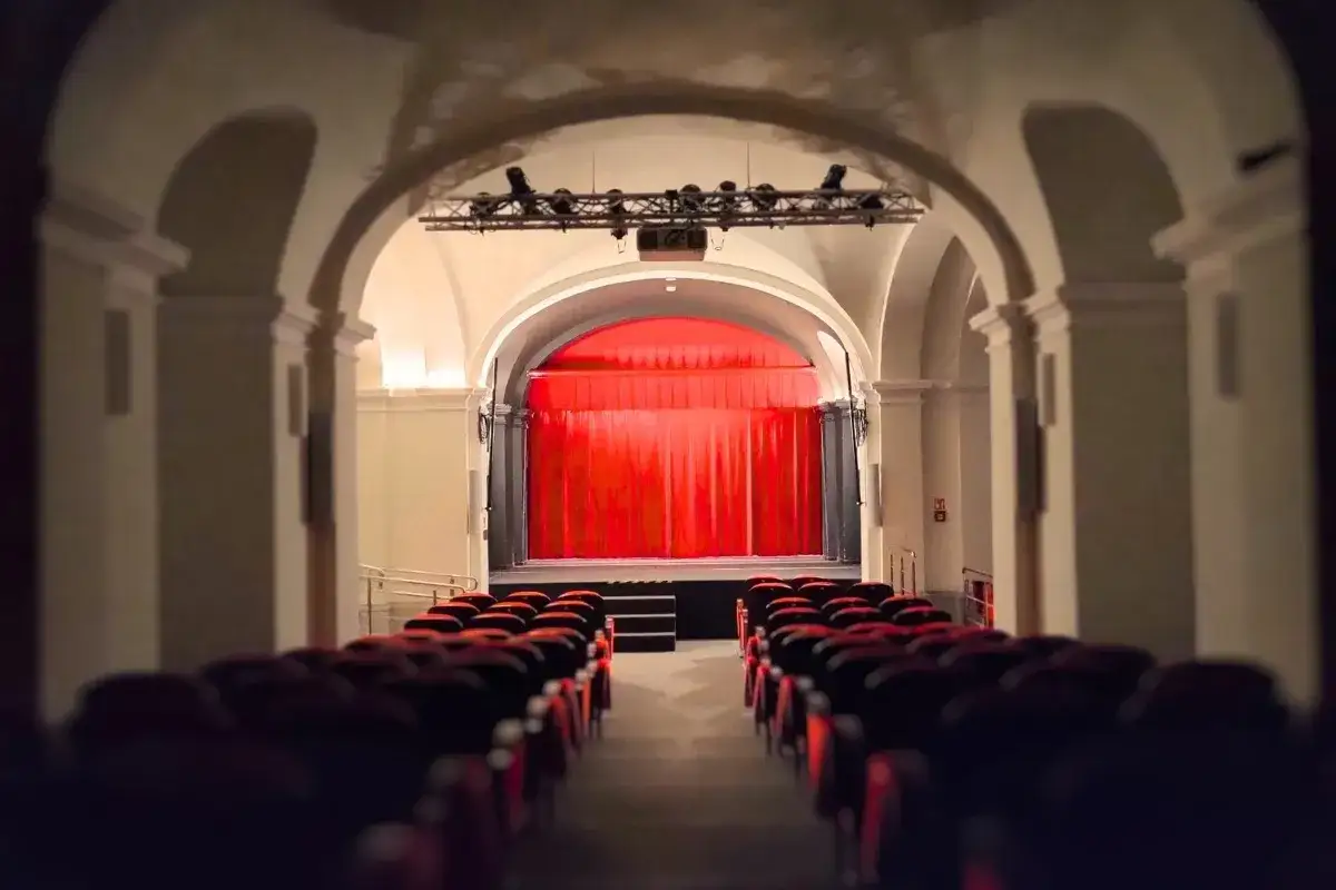 Puste fotele teatralne w Warszawie czekają na widzów. Czerwona kurtyna zaprasza na spektakl. Teatr po angielsku Warszawa.