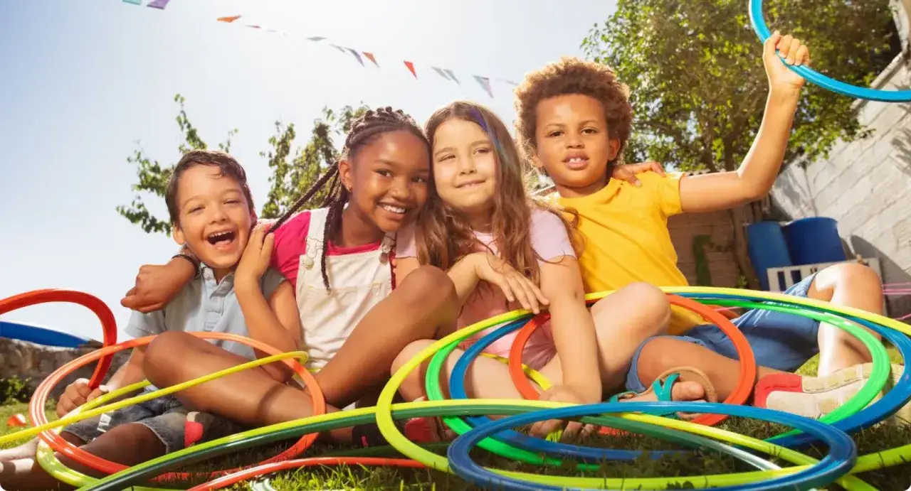 Uśmiechnięci chłopcy i dziewczynki bawią się kolorowymi obręczami. To świetne kreatywne zabawy dla młodzieży na świeżym powietrzu.