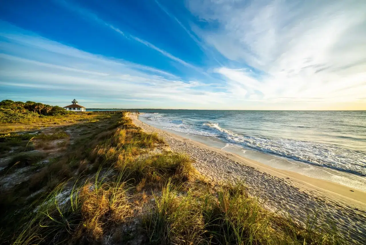Spokojna plaża na Florydzie z latarnią morską w tle. Czy na Florydzie jest bezpiecznie? Tak, to miejsce wygląda na spokojne i bezpieczne.
