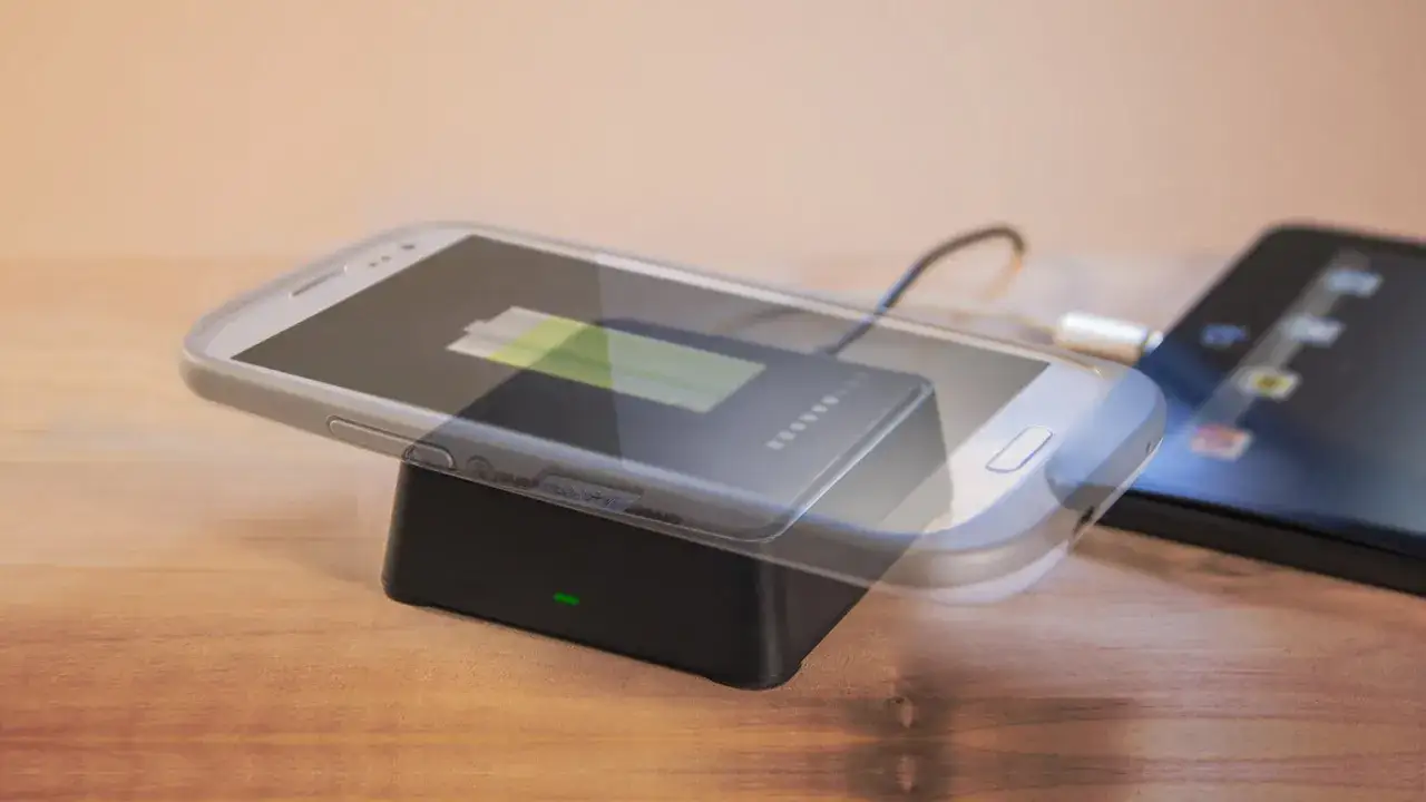 Czy ładowanie bezprzewodowe niszczy baterie? Smartfon na ładowarce indukcyjnej, z widocznym wskaźnikiem baterii.