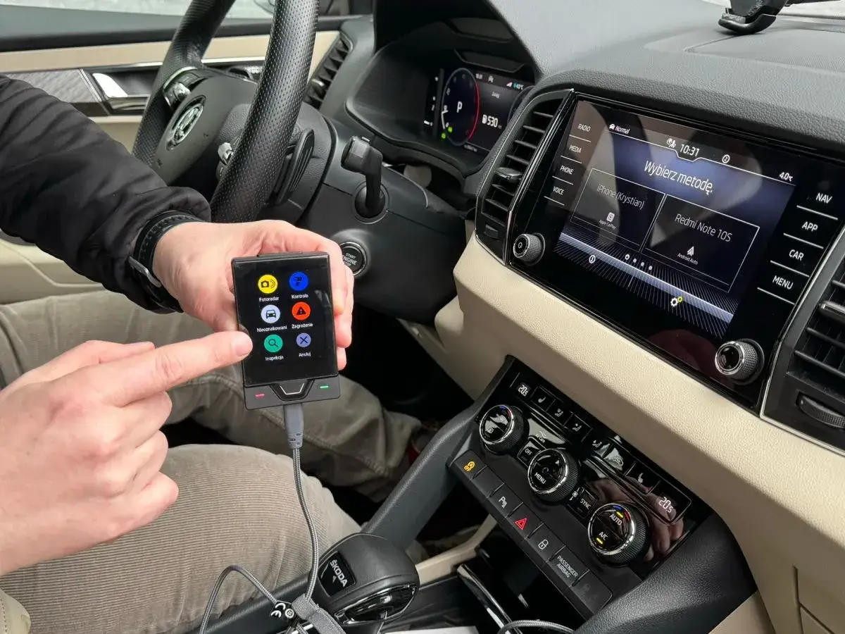 Ręka wskazuje na ekran urządzenia, na kt&oacute;rym widać ikony: fotoradar, kontrola, nieoznakowane, zagrożenie, inspekcja. Czy yanosik działa w niemczech?