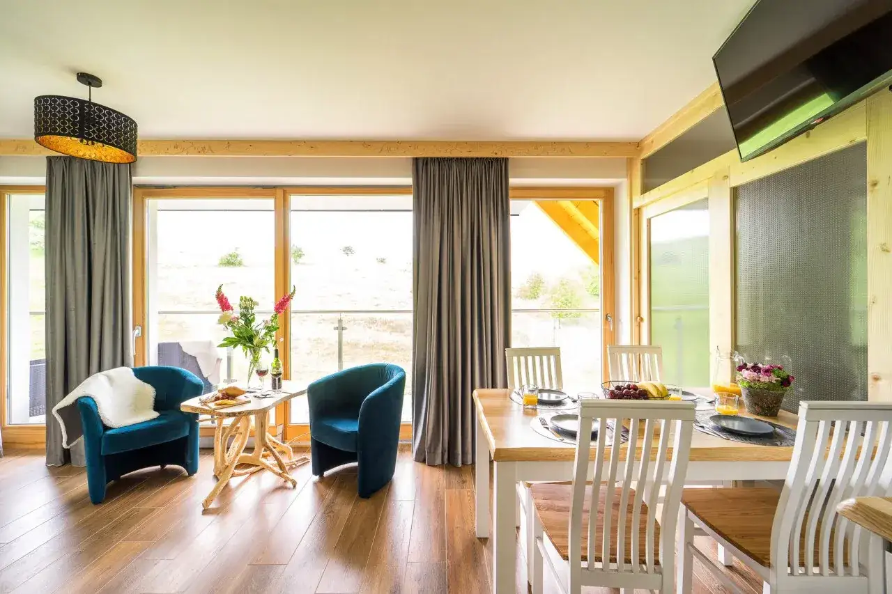 Przytulne pokoje gościnne Bachledzki Wierch. Salon z wygodnymi fotelami i stołem, idealny na rodzinne posiłki.