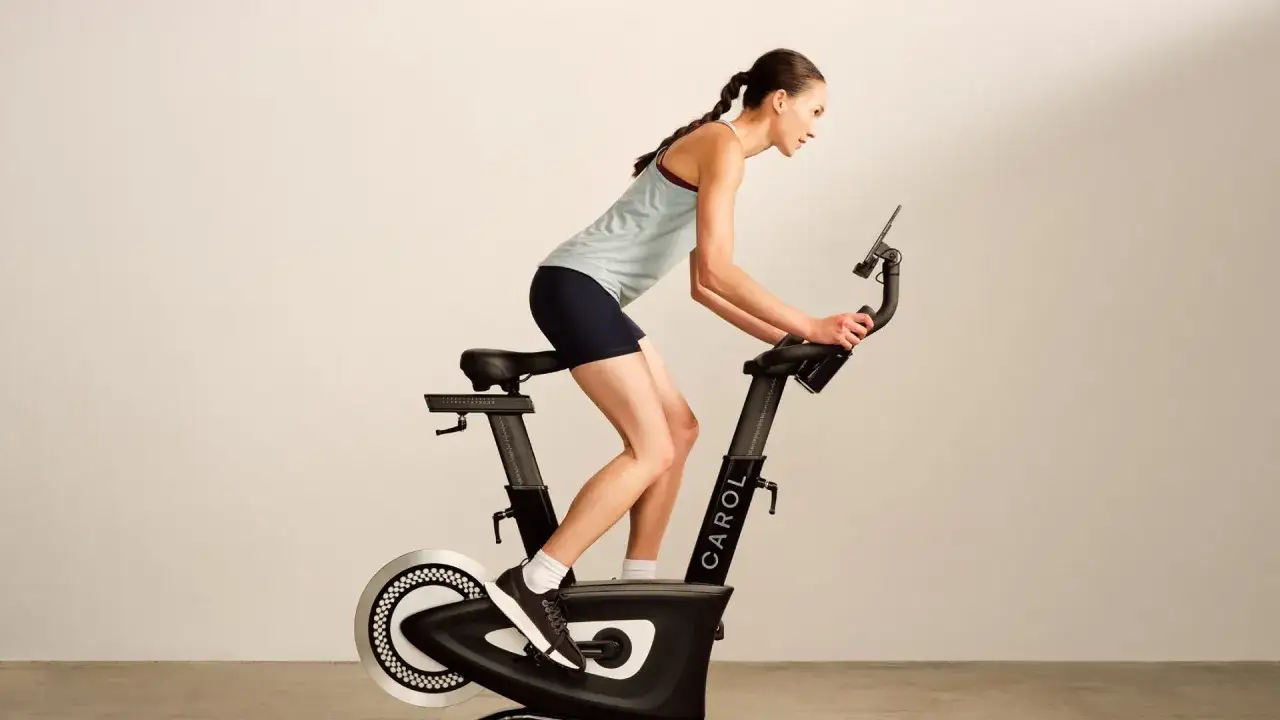 Kobieta ćwiczy na rowerku stacjonarnym. Zastanawiasz się, ile jeździć na rowerku stacjonarnym, by osiągnąć cele?