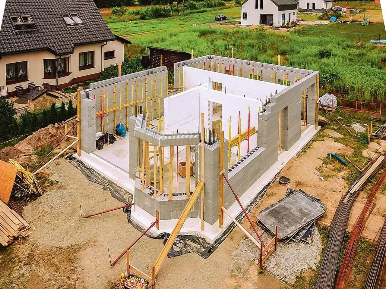 Budowa domu ze styropianu w toku. Ściany z bloczków betonowych i białego styropianu, zbrojenia i drewniane podpory.