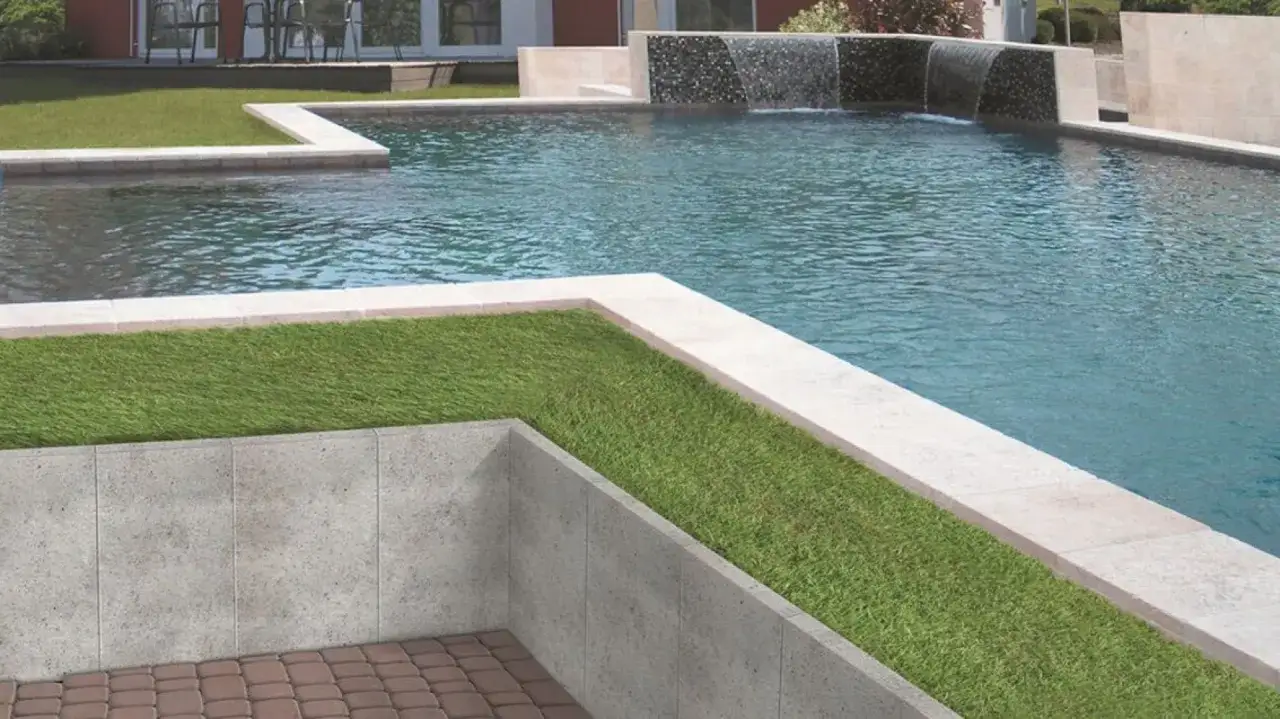 Nowoczesny basen z kaskadą i trawnikiem. Świetny pomysł na murek w ogrodzie, kt&oacute;ry oddziela strefy i dodaje elegancji.